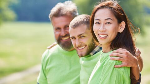 Team mit grünen T-Shirts Drei Menschen mit einem hellgrünen T-Shirt lachen in die Kamera