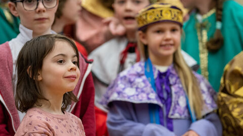 Eine Sternsingerin Ein verkleidetes Mädchen mit Sternsinger Kostüm und Krone, ein anderes kleines Mädchen daneben und weitere Kinder drumherim