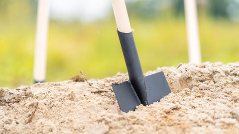 Spatenstich Schaufel steckt in einem Sandhaufen