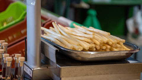Frischer Spargel liegt auf einer Metallwaage und wird eingewogen.