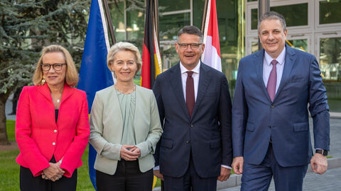 Besuch Merck Ministerpräsident Rhein neben Ursula von der Leyen, Belén Garijo und Kai Beckmann. Sie stehen nebeneinander vor Flaggen.