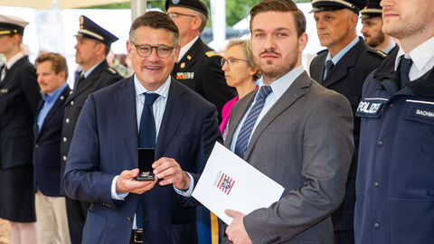 Ministerpräsident Boris Rhein überreicht einem Mann eine Urkunde 