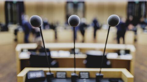 Drei Mikrofone an einem Rednerpult.