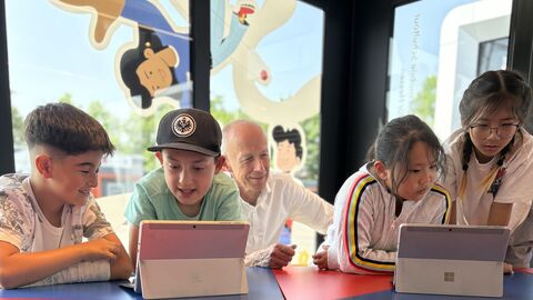 Bildungsminister Armin Schwarz schaut Kindern über die Schulter die ein digitales Lernsystem nutzen