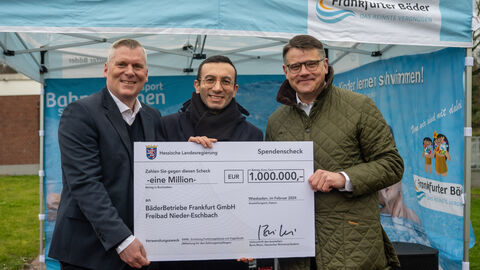 Ministerpräsident Boris Rhein hält gemeinsam mit Dr. Boris Zielinski sowie dem Oberbürgermeister der Stadt Frankfurt und Aufsichtsratsvorsitzenden der Frankfurter BäderBetriebe GmbH Mike Josef einen Scheck in die Kamera