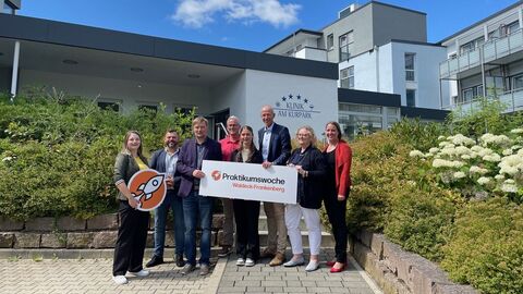 Praktikumswoche 2025 Mehrere Personen stehen vor Klinik und halten ein Schild in Kamera.