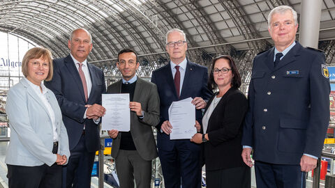 Innenminister Roman Poseck mit Dr. Klaus Vornhusen (Konzernbevollmächtigter der DB für das Land Hessen), Mike Josef (Oberbürgermeister der Stadt Frankfurt am Main), Rocco Stein (Leiter der Bundespolizeiinspektion Frankfurt am Main), Kerstin Jerchel (Geschäftsführung Stadtwerke Verkehrsgesellschaft mbH) und Melanie Kühner (Leitung Bahnhofsmanagement DB InfraGO Personenbahnhöfe) Innenminister Poseck steht mit weiteren Personen im Frankfurter Hauptbahnhof und hält Schreibstücke in die Kamera